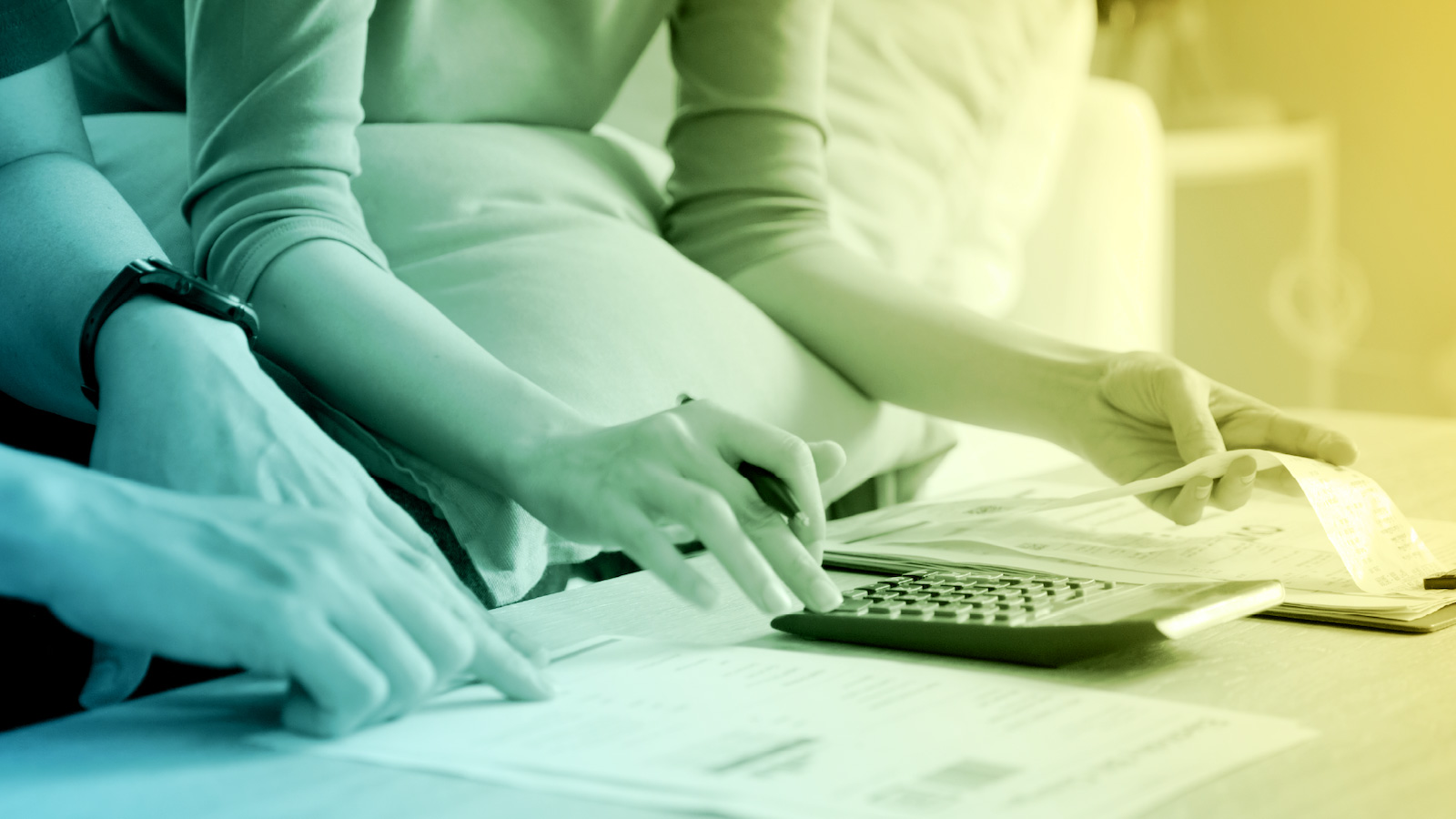 Close-up of people calculating household bills with a calculator and receipts on a table, representing budgeting and energy cost management.