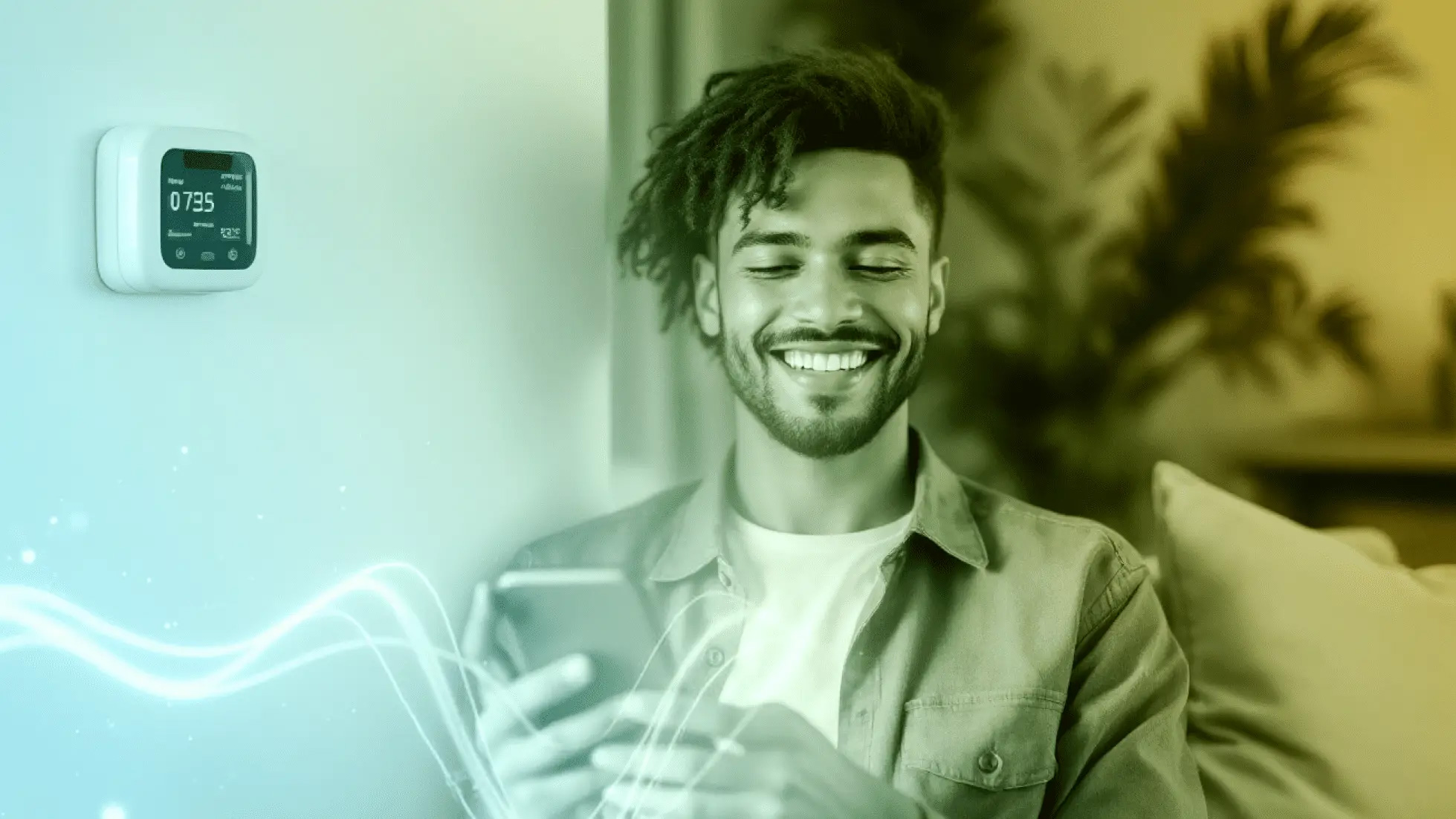 A smiling man checks his smartphone near a digital thermostat, representing easy management of pay-as-you-go electricity accounts from home.